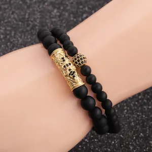 Close-up of matte black bead bracelets with gold crown and cubic zirconia details