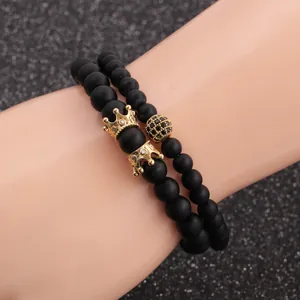 Detail of matte black beads bracelet set featuring golden crown and micro-pave charms