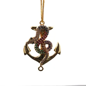 Detalle de un colgante de ancla y serpiente dorada con diamantes de imitación
