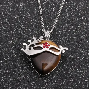 Détail du pendentif en œil de tigre en forme de cœur avec filigrane de masque et strass