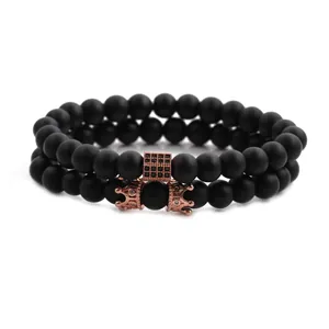Detail of black matte bead bracelet set featuring rose gold crown and cross charms