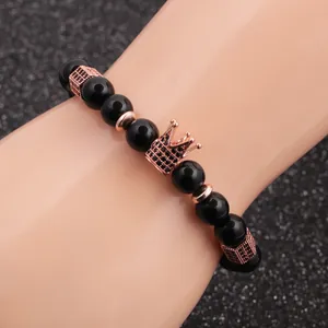 Détail macro des perles d'obsidienne noire de 8 mm avec un charm couronne or rose