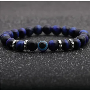 Macro detail of 8mm tiger eye beads and evil eye charm on men's beaded bracelet