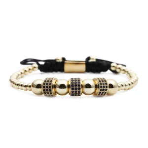 Macro shot of gold beaded bracelet with blue zircon cylinders and adjustable black cord
