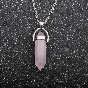 Macro shot of a pink crystal hexagonal pendant on a silver-tone chain over black glitter