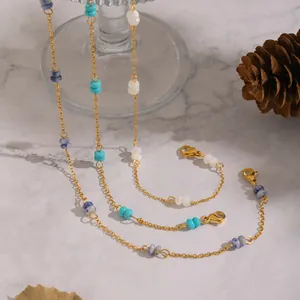 Minimalist gold stainless steel necklaces with natural stone beads layered on marble background