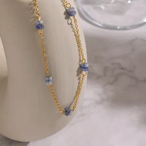 Minimalist gold stainless steel necklace with blue natural stone beads on stone background