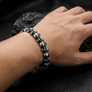 Close-up of punk skull bracelet with vintage finish worn on wrist against dark stones