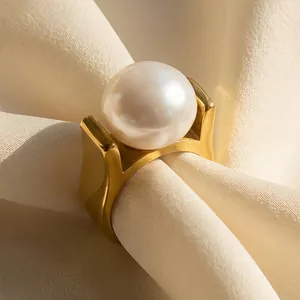 Luxe gold stainless steel ring featuring a large glossy white pearl on silk background