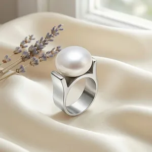 Nahaufnahme eines Perlenrings auf weißem Satin mit eleganten lila floralen Akzenten