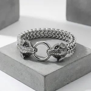 Macro detail of vintage silver zodiac boar heads on a heavy stainless steel woven bracelet