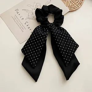 Elegant black satin bow scrunchie with white polka dot patterns for women's hair styling