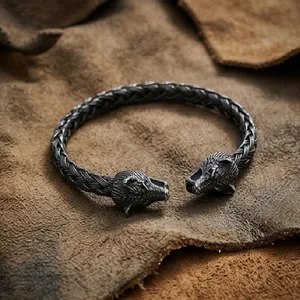 Close-up of Nordic Viking braided bracelet with dual animal head carvings on leather background