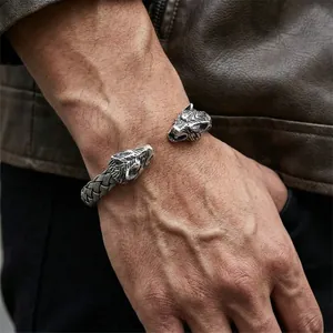 Detail of vintage silver wolf head cuff bracelet with intricate braided texture for men