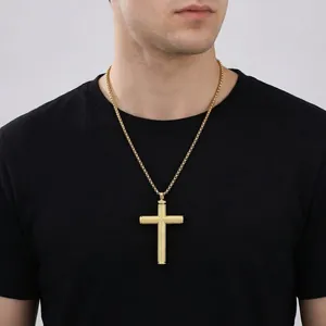 Détail du pendentif croix dorée avec texture moletée sur un t-shirt noir homme