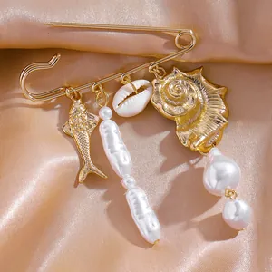 Gros plan d'une broche sur le thème de la mer avec des breloques dorées et des perles