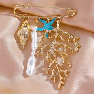 Gros plan détaillé d'une broche dorée thème plage avec coraux, coquillages et perles.