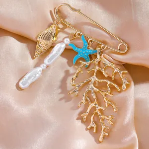 Gros plan d'une broche dorée avec des breloques étoile de mer, corail et perle