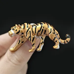 Detailed macro view of a golden tiger enamel brooch pin held to show scale and texture