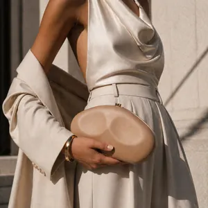 Elegant beige pebble-shaped evening clutch bag for women shown in a luxury fashion setting