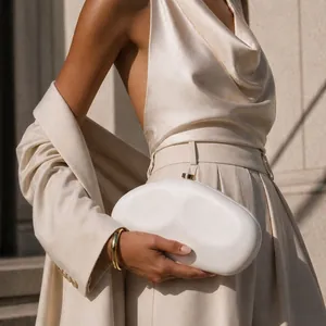 Close-up of elegant white irregular acrylic evening clutch held by model