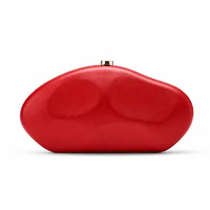 Detail of a red irregular pebble-shaped evening clutch bag with golden clasp.