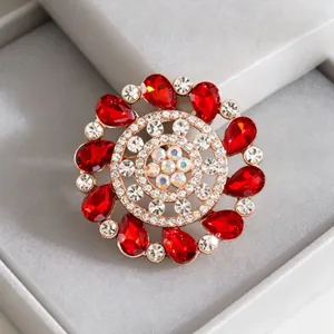 Macro detail of red teardrop gemstone flower brooch with crystals on velvet base