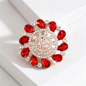 Elegant gold flower brooch with pear-cut red gems and sparkling white crystals