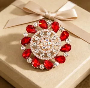 Macro shot of a floral brooch with red gems and crystal core on a ribboned gift box