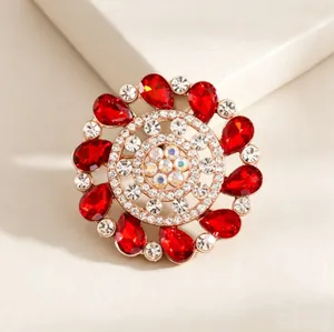 Luxury gold round brooch featuring red pear-cut gems and concentric white rhinestones