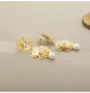 Λήψη macro από χρυσά κλιπ σκουλαρίκια λουλούδια με πέρλες και κρυστάλλινες λεπτομέρειες
