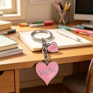 Rosafarbener herzförmiger MOM Schlüsselanhänger aus Metall mit LOVE Charm auf Holz