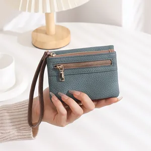 Detail of grey-blue litchi grain leather purse with dual gold zippers and wristlet
