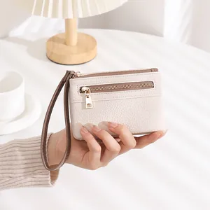 Close-up of cream white lychee texture wallet with dual zippers and brown wrist strap
