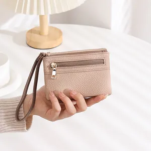Detail of beige lychee leather wallet with double zippers and brown wristlet strap