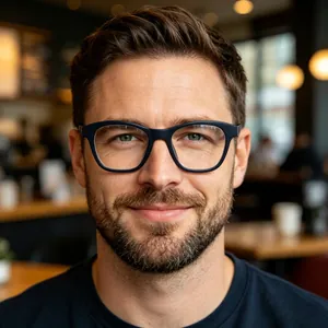 Portrait of a man wearing stylish dark blue retro cat-eye eyeglasses frames in a cafe