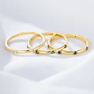 Detail of three stackable gold rings with white, green and blue zircon gemstones