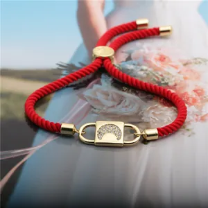 Macro shot of red braided rope bracelet with a gold crescent moon zircon charm
