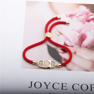 Close-up of a red braided adjustable rope bracelet with a gold-plated heart lock pendant