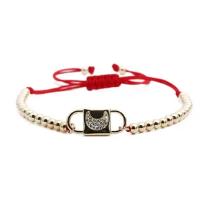 Detail of red braided bracelet featuring a gold plate with crescent moon zircon stones