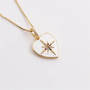 Detalle del colgante de corazón con esmalte blanco y circonitas de colores en dorado
