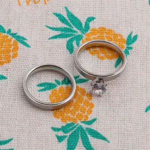 Close-up of matte silver couples rings with a round zircon on a patterned fabric