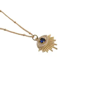 Macro-opname van gouden evil eye hanger met blauwe zirkoon en fijne kralenketting
