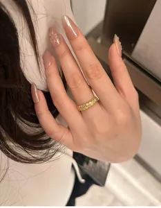 Close-up of golden wheat-inspired woven ring with sparkling white cubic zirconia stones