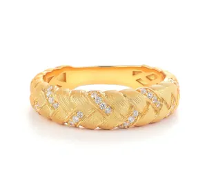 Macro view of woven golden ring with brushed finish and inlaid clear gemstones