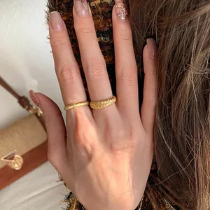 Golden wheat-braid and slim diamond rings worn on hand for an elegant, vintage aesthetic