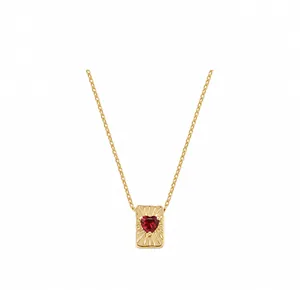 Detailopname van gouden vierkante hanger met rode hartvormige edelsteen en ketting