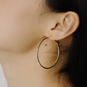 Minimalist large gold hoop earrings with polished finish shown on a female model