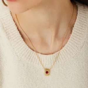 Franse vintage gouden ketting met rode edelsteen gedragen op een beige trui