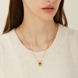 Franse vintage gouden ketting met vierkante harthanger en rode zirkoon op een model
